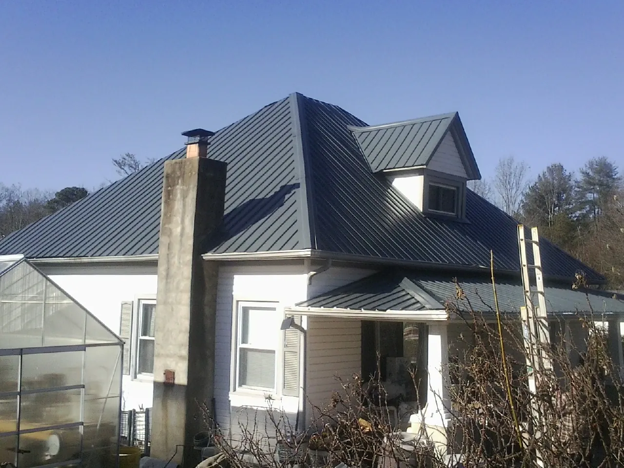 Dark blue standing seam metal roof on a white farmhouse with dormer — Slate & Tile Roof Repair by Roofing Brothers in Little Hocking