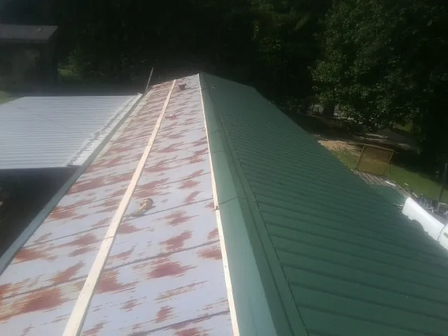 Old rusted panels beside newly installed green metal roofing — Wind Damage Roof Repair by Roofing Brothers in Little Hocking