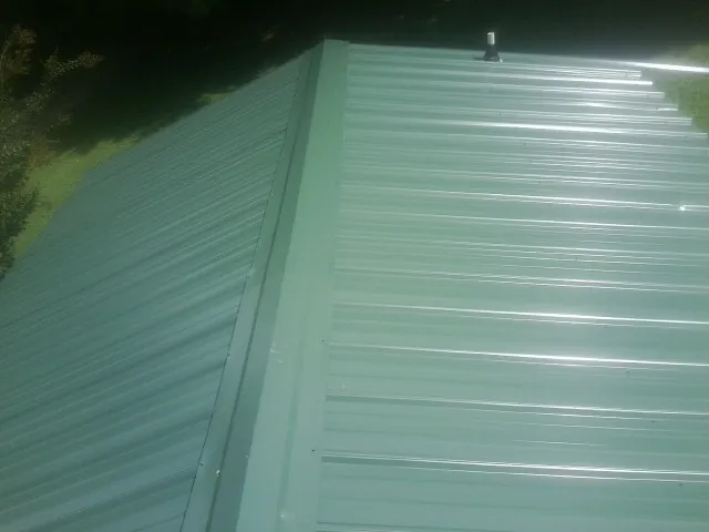 New green metal panels meeting at the ridge of a roof — Flat Roof Repair work by our crew in Little Hocking