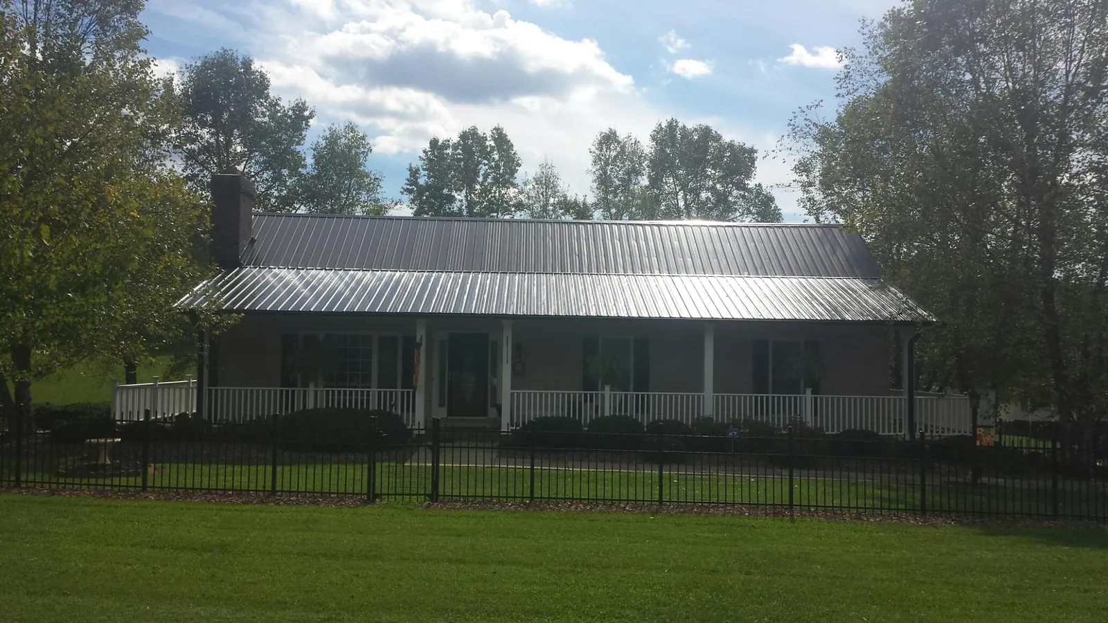Gray metal roof on a brick ranch with a full width front porch — Gutter Guard Installation work by our crew in Little Hocking