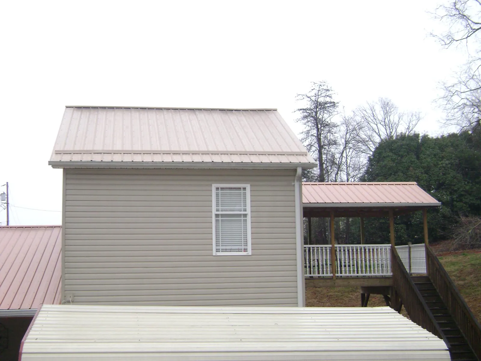 Tan metal roofs on a two story addition and attached porch, from a Roof Replacement job in Little Hocking