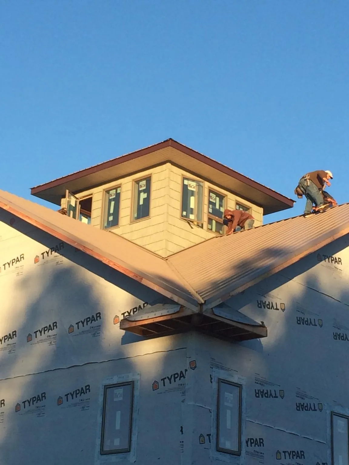 Roofers working around a rooftop cupola on a new metal roof at sunset — Roof Waterproofing in Little Hocking by Roofing Brothers